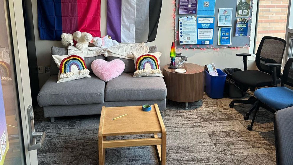 VU 722 decorated with pride flags, and events bulliten board, and rainbow pillows on a grey couch